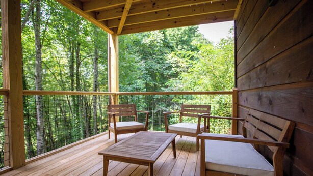 A wooden deck with two chairs and a table, overlooking a forested area. - Pristine Cabin in Heart of Boone (Vilas)