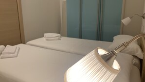 Una habitación de hotel con dos camas, una lámpara de noche y un espejo.