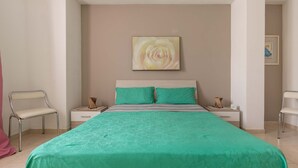 A bedroom with a bed, two nightstands, a chair, a framed picture on the wall, and a door leading to another room. - 1817 Villetta Ginetta (Maruggio)