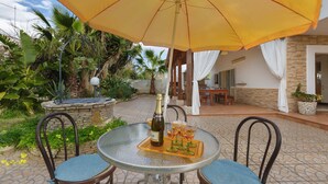 A round table with a yellow umbrella, two chairs, a bottle of champagne, and three glasses on a tray. - 1817 Villetta Ginetta (Maruggio)