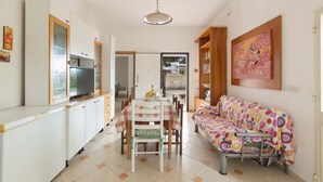 A compact living space with a dining area, kitchenette, and a sofa. - 1817 Villetta Ginetta (Maruggio)