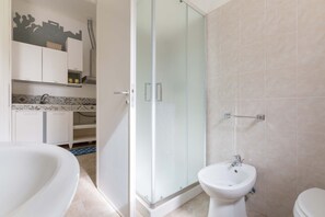 A modern bathroom with a glass-enclosed shower, a white sink, and a toilet.