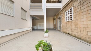 A clean, modern building with a tiled floor, a balcony, and a potted plant in the foreground. - 1866 Stella Bianca Luxury Suite (Lecce)