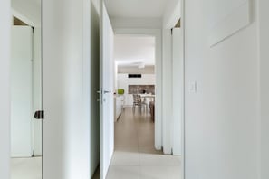 A hallway leading to a dining area with a kitchen in the background.