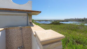 A coastal building with a tiled shower area and a view of the sea and marshland. - 1939 Villetta Camilla (Lecce)