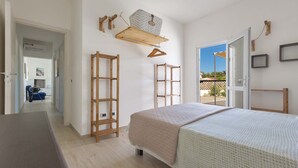 A bedroom with a bed, wooden furniture, a hanging basket, and a view of the outside. - 1939 Villetta Camilla (Lecce)