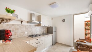 Una cocina moderna con estufa a gas, refrigerador de acero inoxidable y armarios de colores claros.