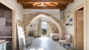 A rustic interior with a stone archway, a wooden ceiling, and a view to the outside. - 1891 Falcon Home Resort (Lizzanello)