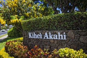 Located in Kihei Akahi, this property features a serene landscaped area with a stone wall and lush greenery.