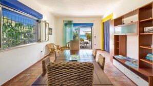 A spacious living area with a long wooden table, wicker chairs, and a bookshelf. - 1906 Villa Sara (Porto Cesareo)