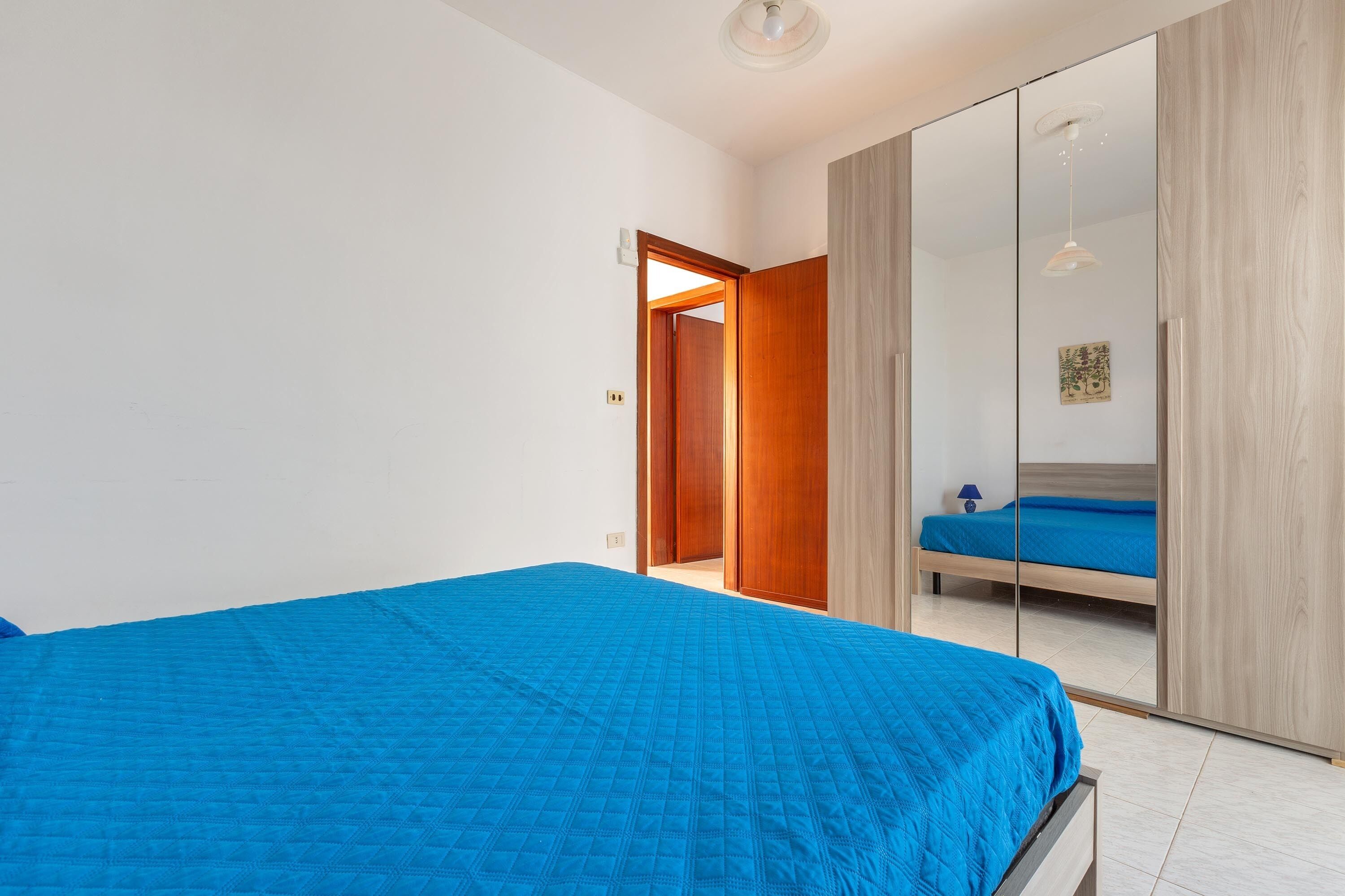 Une chambre à coucher avec un grand lit, une armoire et une porte donnant sur une autre pièce.