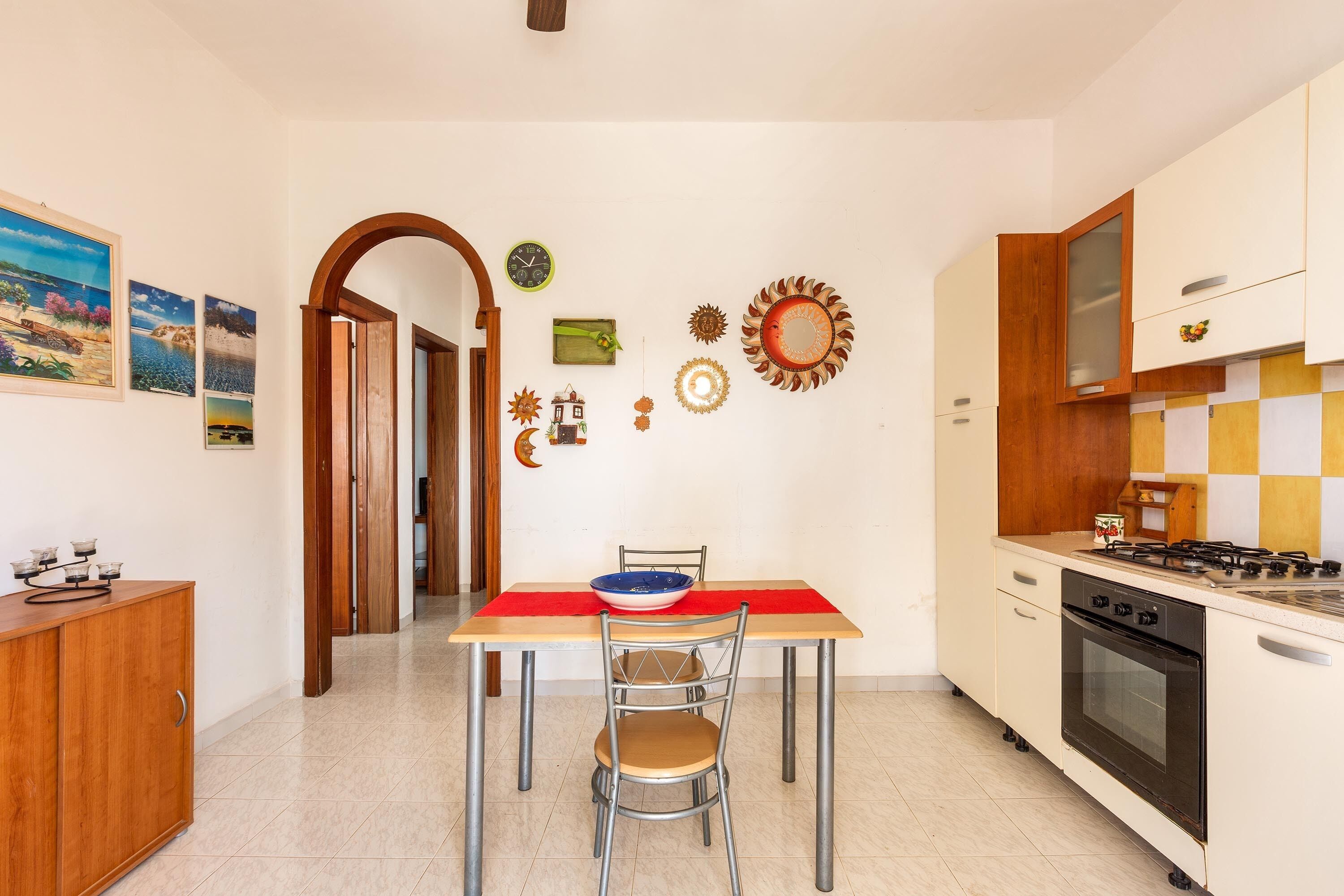 Una cocina con una mesa de comedor, sillas, una estufa y varias decoraciones en las paredes.