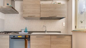 A modern kitchen with wooden cabinets, a built-in oven, and a stainless steel sink. - 1861 La Casa di Giulia (Otranto)