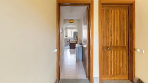 A hallway leading to a dining area with a wooden door and a tiled floor. - 1861 La Casa di Giulia (Otranto)
