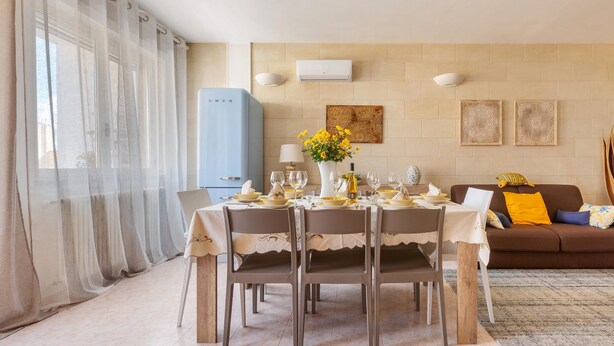 A dining area with a table set for four, a sofa, and a blue appliance in the background. - 1861 La Casa di Giulia (Otranto)