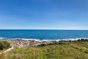 A coastal landscape with rocky terrain and a clear blue sky.