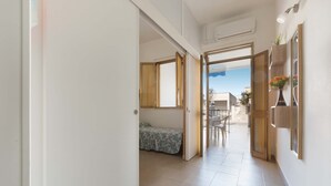 A hallway with a bed, a dining area, and a view of the outside. - 1826 Villetta Solaire (Porto Cesareo)