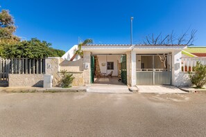 A house with a gated entrance, a covered porch, and a small patio area with chairs. - 1869 Villetta Specchio di Mare (Porto Cesareo)