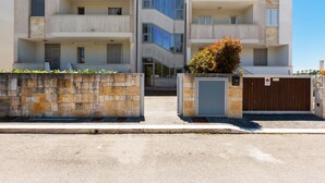 Um edifício moderno de vários andares com varandas, portão de entrada e muro de pedra.