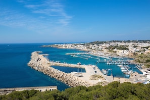 Un pueblo costero con un puerto deportivo, un rompeolas rocoso y edificios residenciales.