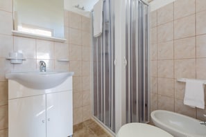 Un baño con un lavamanos blanco, cabina de ducha y bañera.