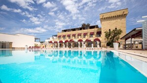Une piscine à l’eau d’un bleu cristallin, entourée d’un bâtiment doté de nombreux balcons et d’espaces de détente en plein air.