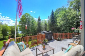 A deck with outdoor furniture, a grill, and a flag. - Brooklake - Custom built home on Dodge Pond, with 250' on Dodge Pond Stream too (Rangeley)