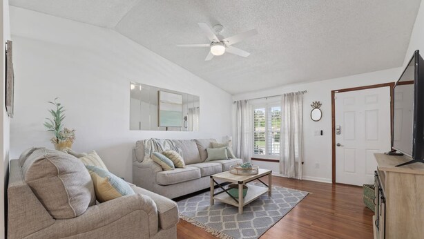 A spacious living room with a grey sofa, a coffee table, and a television on a wooden stand. - Comfy Mayo Retreat: Pool & Close to Beach (Jacksonville Beach)