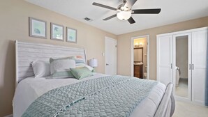 A bedroom with a bed, a ceiling fan, a wardrobe, and a door leading to a bathroom. - Comfy Mayo Retreat: Pool & Close to Beach (Jacksonville Beach)