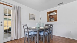 A dining area with a wooden table and four chairs, a painting on the wall, and a wooden cabinet above the table. - Comfy Mayo Retreat: Pool & Close to Beach (Jacksonville Beach)