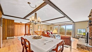 A spacious dining area with a long table, wooden chairs, and a chandelier.