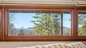 A room with a large window offering a view of trees and mountains.