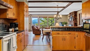 A kitchen with wooden cabinets, a dining area with a table and chairs, and a view of the outdoors.