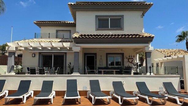 A two-story building with a swimming pool, sun loungers, and a covered patio area. -  Luxury Front-Line Golf Villa with Private Pool & Panoramic Views (Orihuela)