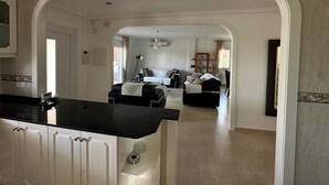 A spacious hotel room with a large bed, a desk, and a view of the living area. -  Luxury Front-Line Golf Villa with Private Pool & Panoramic Views (Orihuela)