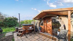 A wooden cabin with a stone patio, a hot tub, and a wooden deck. - Luxury Pod-sleeps 2-hot Tub-pets-garden (Sheerness)