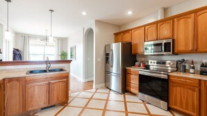 Una cocina moderna con armarios de madera, electrodomésticos de acero inoxidable y suelo de baldosas.