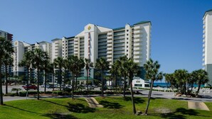 A hotel with multiple white buildings, palm trees, and a clear blue sky.