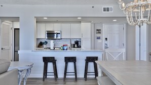 A modern kitchen with white cabinets, a central island, and bar stools.