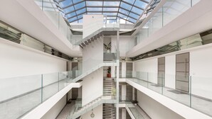 Un atrium à plusieurs niveaux, doté de rampes en verre et d’un escalier central.