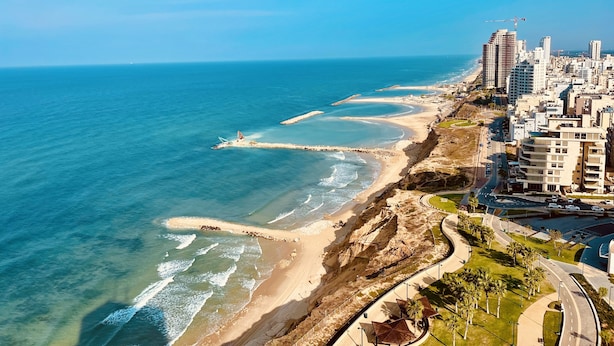 Un paisaje urbano costero con playa, rascacielos y cielo azul despejado.