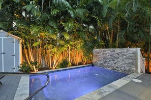 Une piscine à l’intérieur bleu, entourée d’une végétation luxuriante et d’une clôture en bois.