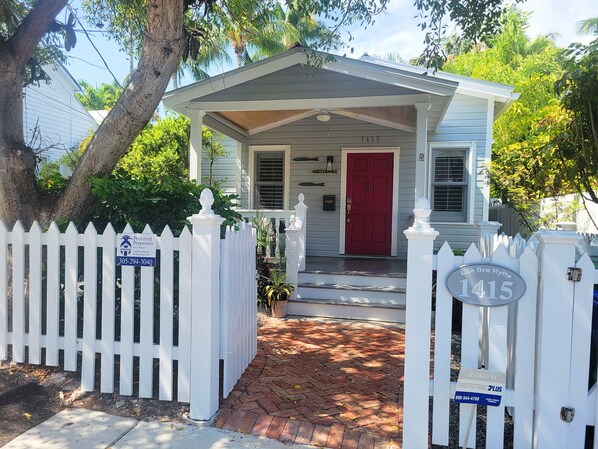 A white house with a red door, a mailbox, and a number 1415 sign.