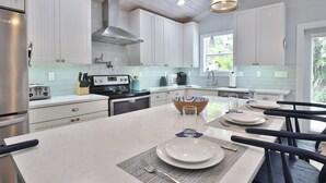 Una cocina moderna con armarios blancos, electrodomésticos de acero inoxidable y una isla central con asientos.