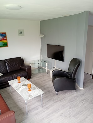 A living room with a sofa, a coffee table, a TV, and a chair.
