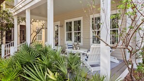 A covered porch with white columns, a round table, and chairs. - WaterColor on Dragonfly Park | Porches & Park Views (Santa Rosa Beach)