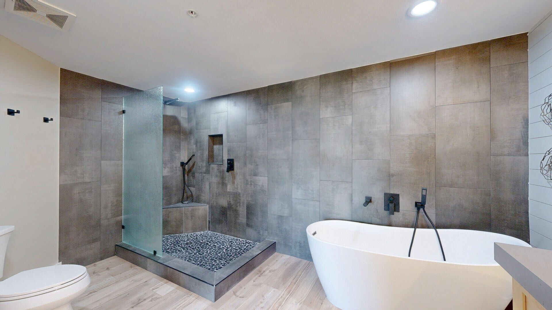 A modern bathroom with a freestanding bathtub, a glass-enclosed shower, and a toilet.