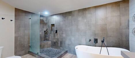 A modern bathroom with a freestanding bathtub, a glass-enclosed shower, and a toilet.
