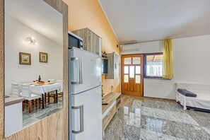 A compact living space with a dining area, a kitchenette, a sofa, and a door leading to an outdoor area.