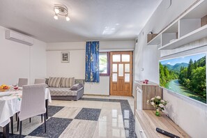 Un moderno salón con un sofá, una mesa de comedor y un televisor que muestra una vista panorámica.